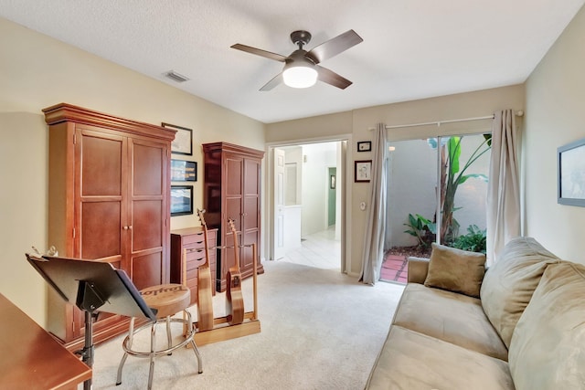 interior space featuring ceiling fan, light colored carpet, and a textured ceiling