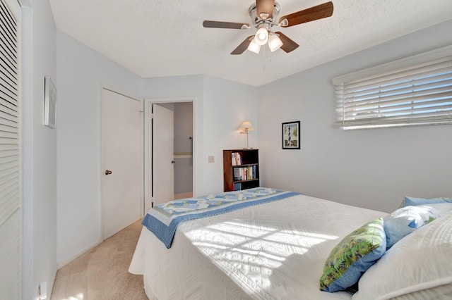 carpeted bedroom featuring ceiling fan, a closet, and a textured ceiling