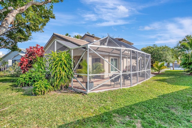 rear view of property with a yard, a patio, and glass enclosure