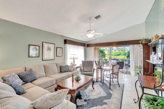 living room with ceiling fan, a textured ceiling, light tile patterned floors, and lofted ceiling