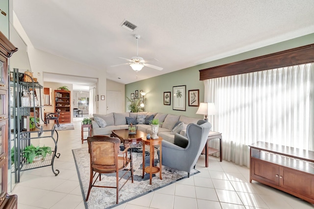 tiled living room with ceiling fan, a textured ceiling, and lofted ceiling