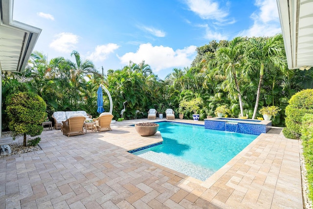 view of swimming pool featuring a pool with connected hot tub and a patio