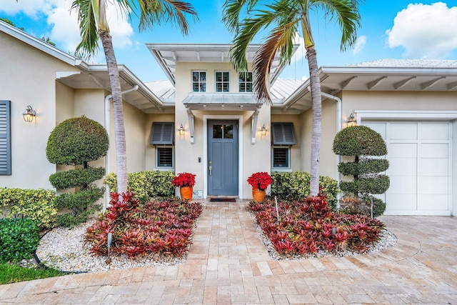 view of exterior entry featuring a garage and stucco siding