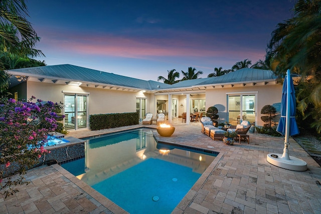 back of house with an outdoor pool, an outdoor fire pit, a patio area, and stucco siding