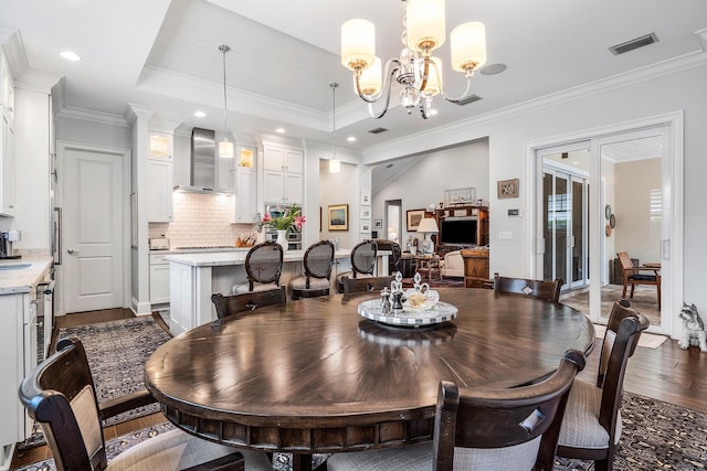 dining area with a chandelier, visible vents, dark wood-style floors, a tray ceiling, and crown molding