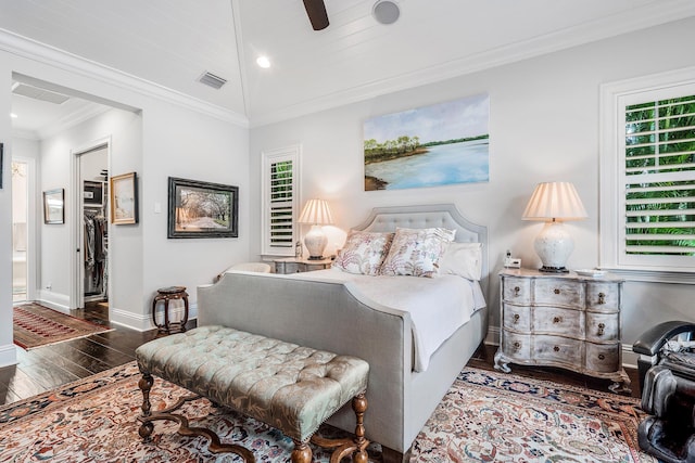 bedroom featuring baseboards, visible vents, ornamental molding, wood finished floors, and a spacious closet