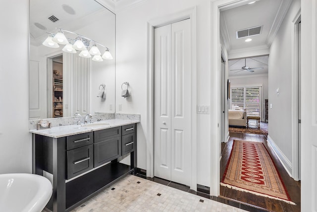 bathroom with a closet, vanity, visible vents, and crown molding