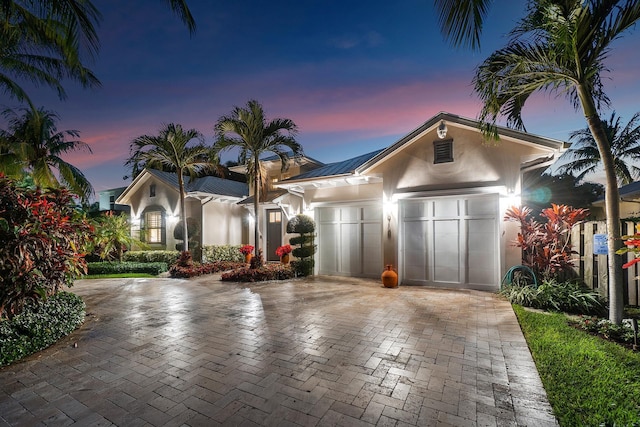 view of front facade with decorative driveway, an attached garage, and stucco siding