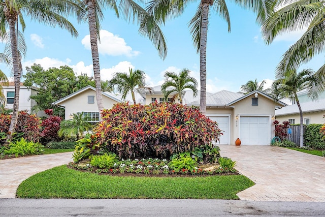 view of front of house featuring a garage, decorative driveway, fence, and stucco siding