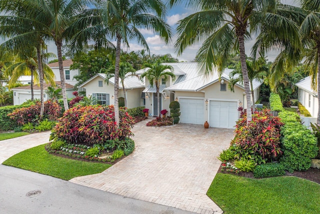 view of front of house with an attached garage, decorative driveway, and stucco siding