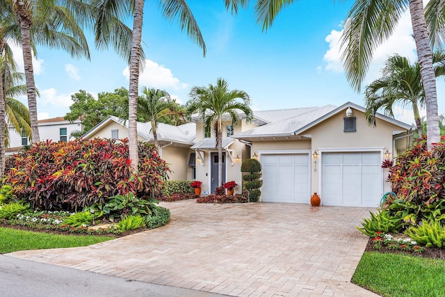 view of front of property featuring a garage, decorative driveway, and stucco siding