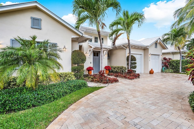 view of front of house with an attached garage, decorative driveway, and stucco siding