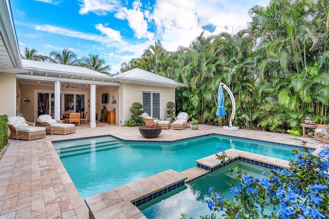 view of pool featuring a ceiling fan, a pool with connected hot tub, a patio, and an outdoor hangout area