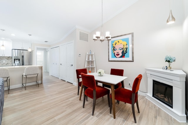 dining room with lofted ceiling, crown molding, a chandelier, and light hardwood / wood-style floors