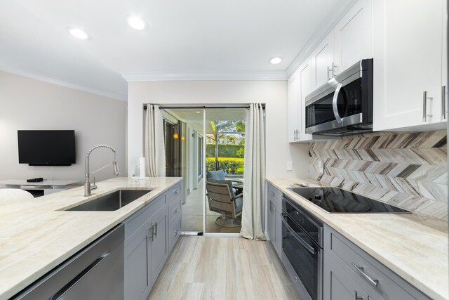 kitchen with gray cabinets, ceiling fan, appliances with stainless steel finishes, light stone counters, and sink