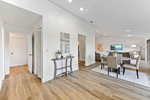 dining room featuring lofted ceiling and light hardwood / wood-style floors