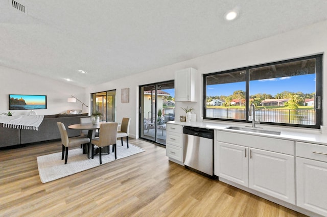 kitchen featuring sink, vaulted ceiling, light wood-type flooring, dishwasher, and white cabinets