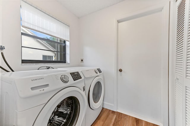 clothes washing area featuring separate washer and dryer and light hardwood / wood-style floors