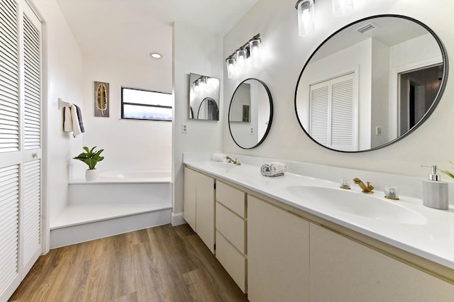 bathroom with vanity, wood-type flooring, and a tub to relax in