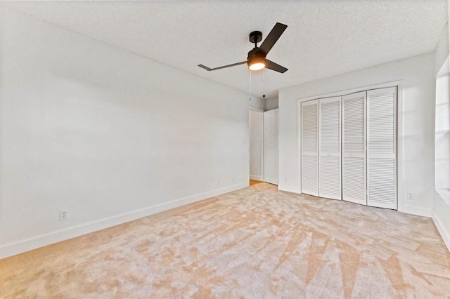 unfurnished bedroom with ceiling fan, light colored carpet, a closet, and a textured ceiling