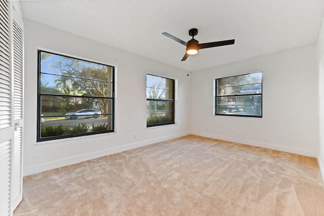 spare room with ceiling fan and light carpet