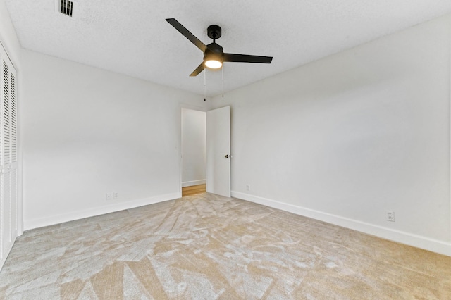 unfurnished room with ceiling fan, light colored carpet, and a textured ceiling