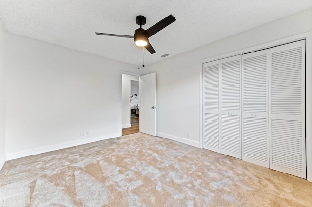 unfurnished bedroom with light carpet, ceiling fan, a closet, and a textured ceiling