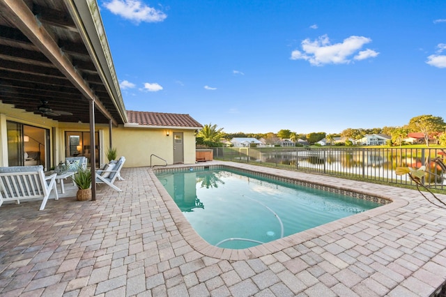 view of swimming pool featuring a water view, ceiling fan, and a patio area