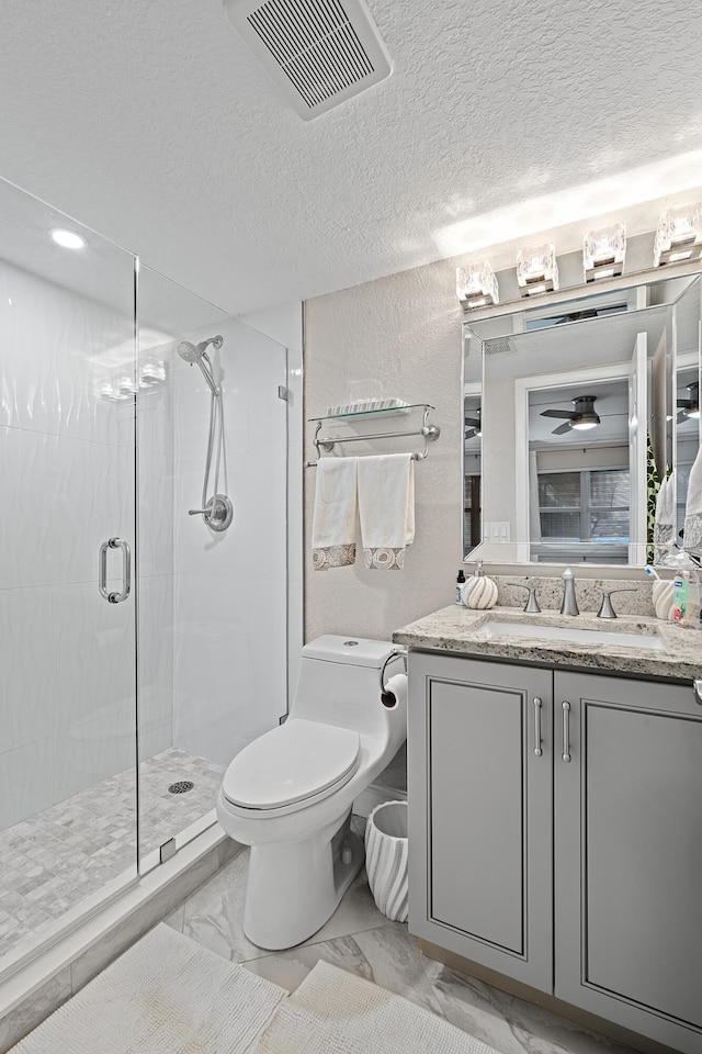 bathroom with vanity, toilet, a shower with door, and ceiling fan