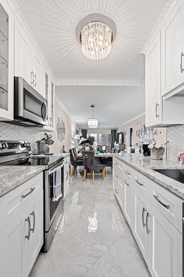 kitchen featuring white cabinets, a chandelier, crown molding, and stainless steel appliances