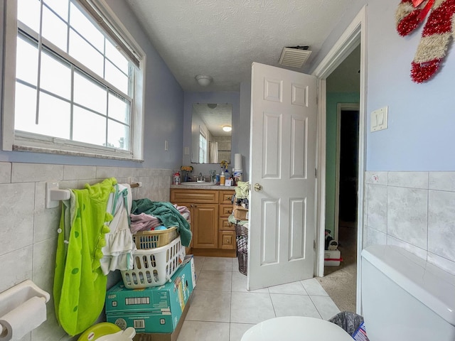 bathroom featuring toilet, tile patterned flooring, tile walls, a textured ceiling, and vanity