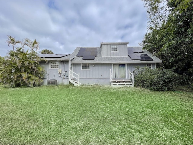 rear view of house featuring central AC unit and a yard