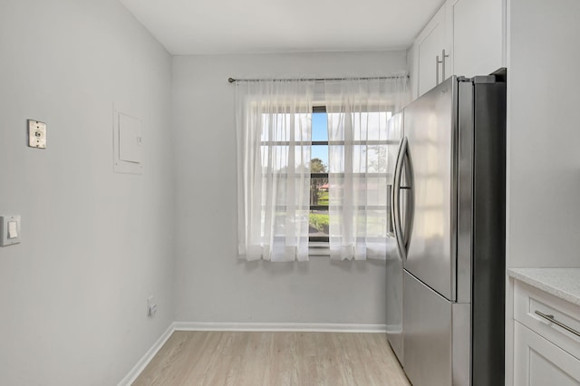 kitchen with stainless steel refrigerator with ice dispenser, light hardwood / wood-style flooring, and white cabinets