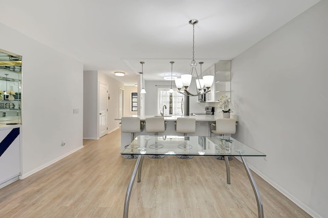 dining space with a notable chandelier, sink, and light hardwood / wood-style floors