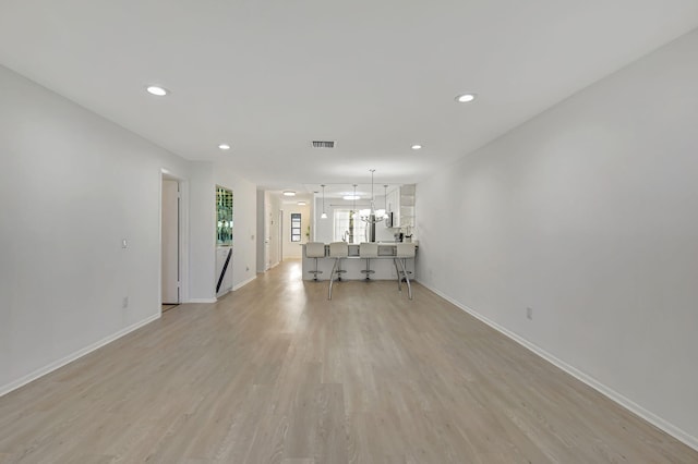 unfurnished living room featuring light hardwood / wood-style flooring and a notable chandelier