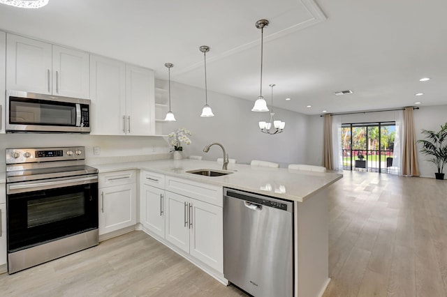 kitchen with white cabinetry, kitchen peninsula, appliances with stainless steel finishes, pendant lighting, and sink