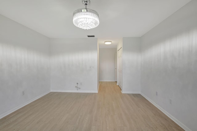 empty room with an inviting chandelier and light hardwood / wood-style floors