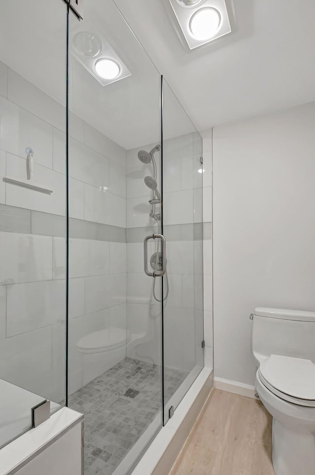 bathroom with toilet, hardwood / wood-style floors, and a shower with door