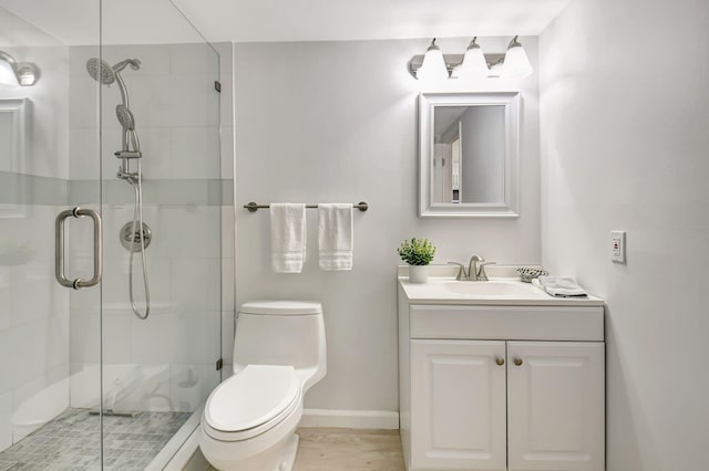 bathroom featuring a shower with shower door, toilet, and vanity