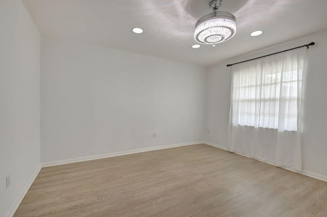 spare room with light hardwood / wood-style floors and a chandelier