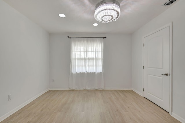 unfurnished room featuring light wood-type flooring and a chandelier