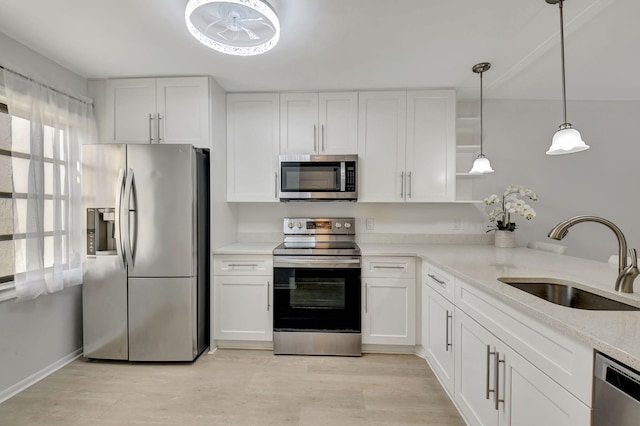 kitchen with white cabinetry, appliances with stainless steel finishes, hanging light fixtures, light hardwood / wood-style flooring, and sink