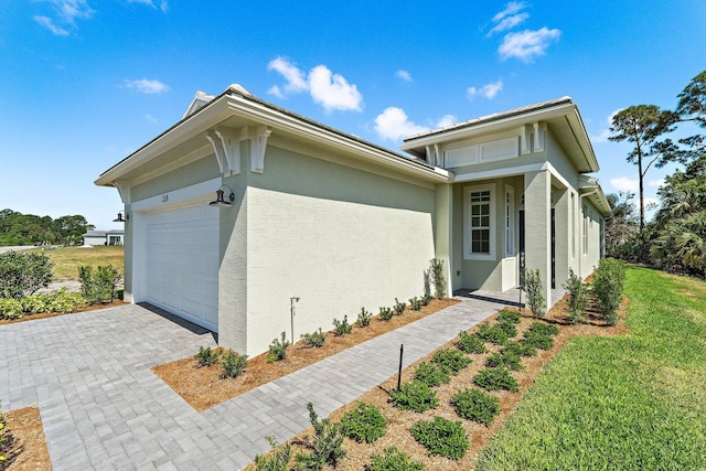 359 SE Via Sangro, Port Saint Lucie, FL 34952 - view of home's exterior featuring stucco siding, an attached garage, and decorative driveway