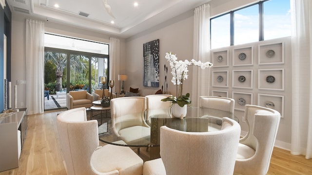 dining space with light hardwood / wood-style floors and a raised ceiling