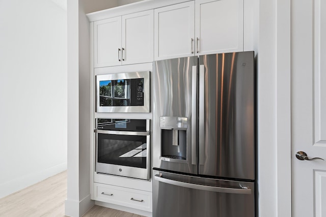 359 SE Via Sangro, Port Saint Lucie, FL 34952 - kitchen with stainless steel appliances, light wood-style flooring, white cabinetry, and baseboards