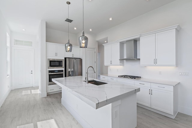 359 SE Via Sangro, Port Saint Lucie, FL 34952 - kitchen with a sink, stainless steel appliances, wall chimney range hood, a kitchen island with sink, and light wood-style floors