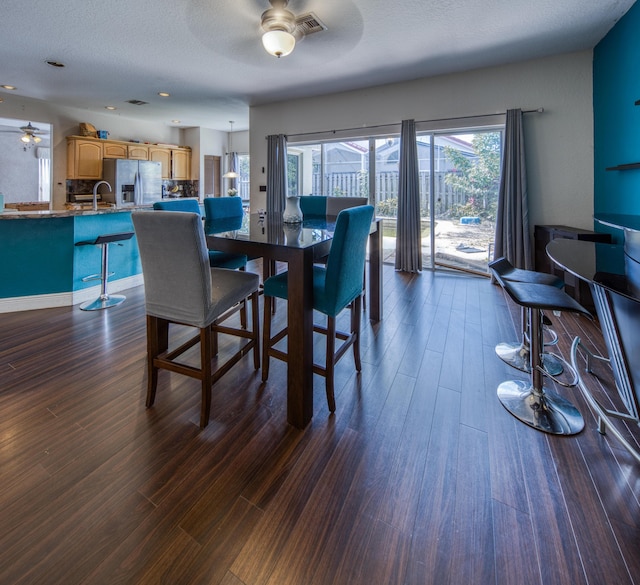 dining room with a ceiling fan, visible vents, and dark wood-type flooring