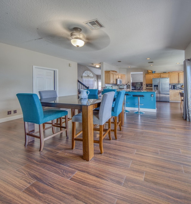 dining space with visible vents, dark wood finished floors, and a textured ceiling