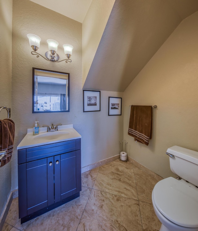 bathroom featuring baseboards, vaulted ceiling, vanity, and toilet