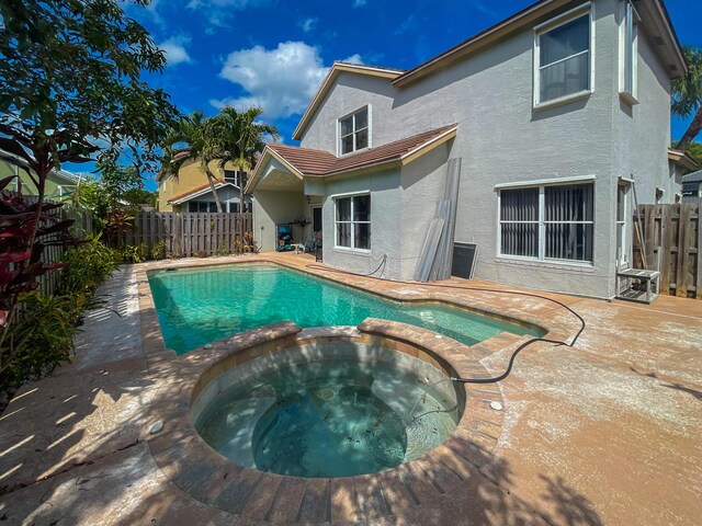 view of swimming pool featuring a pool with connected hot tub and a fenced backyard